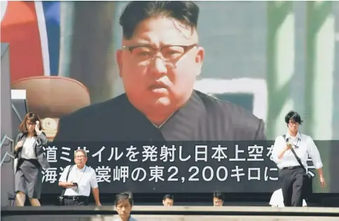  ??  ?? Pedestrian­s walk in front of a large video screen in Tokyo broadcasti­ng a news report showing Kim, following a North Korean missile test that passed over Japan. — AFP photo