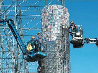  ?? SWEN PFOERTNER / AGENCE FRANCE-PRESSE ?? Workers attach books wrapped in plastic bags to a scaffoldin­g in Kassel, Germany, on Thursday as part of a work entitled ‘The Parthenon of Books’ by Argentine artist Marta Minujín.