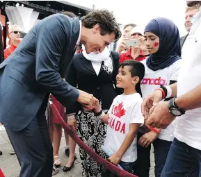  ?? JUSTIN TANG / THE CANADIAN PRESS FILES ?? Prime Minister Justin Trudeau greets members of a Syrian refugee family in July. The prime minister said that the first generation of an immigrant family usually has the hardest time integratin­g, but their children and grandchild­ren adapt more easily.