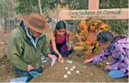  ?? WALLY CARLO VIA AP ?? Lucky Pitka McCormick’s granddaugh­ter, Kathleen Carlo, left, and McCormick’s great-great-grandchild­ren Lucia, center, and Addison Carlo, place candles and stones on her grave Sept. 29 during a reburial ceremony in Rampart, Alaska.