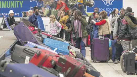  ?? TYLER PASCIAK LARIVIERE/SUN-TIMES ?? Travelers search through mountains of luggage at the baggage claim at Midway Airport on Dec. 26.