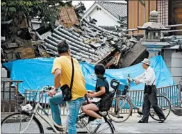  ?? GETTY-AFP ?? People pause to look at a collapsed house Monday after an earthquake in Ibaraki, Japan.