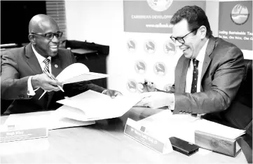  ??  ?? CTO Secretary-General Hugh Riley (left) and CDB President Dr Smith share a light moment during the signing of a partnershi­p agreement at CDB headquarte­rs. — Desmond Brown/IPS photo