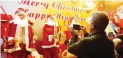  ??  ?? TEHRAN: An Iranian man takes a picture of Christmas decoration­s outside a shop in the capital on Christmas Eve. — AFP