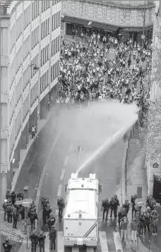  ?? LUCAS BARIOULET / AFP ?? A water cannon sprays in front of protesters wearing yellow vests near the Arc de Triomphe in Paris on Saturday.