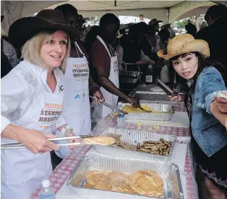  ?? JEFF MCINTOSH/THE CANADIAN PRESS ?? Premier Rachel Notley serves up pancakes with nearly 50 NDP legislator­s at the annual premier's breakfast on Monday. The group is trying to win over financiall­y weary Calgarians.