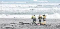  ?? PHOTO: JANNA SHERMAN ?? Rough seas . . . Searchers on the beach at Hokitika yesterday.
