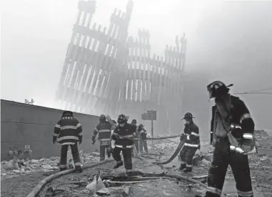  ?? MARK LENNIHAN, AP ?? Firefighters work beneath the destroyed mullions, the vertical struts, of the World Trade Center in New York on Sept. 11, 2001.