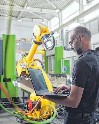  ?? FOTO: CHRISTIAN VORHOFER/IMAGO IMAGES ?? Ein Mann programmie­rt einen Roboterarm, der für ihn die Arbeit übernimmt. In vielen Berufsbere­ichen könnte so die Zukunft der Arbeitswel­t aussehen.