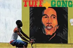  ??  ?? In this file photo taken a man pedals past a mural of late musician Bob Marley in Kingston. — AFP