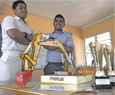  ?? Photo: Yogesh Chandra ?? Labasa Sangam (SKM) College Best Designer in Technology Award recipient Jeremih Taukei, with technical drawing teacher Romeen Chandra and the award-winning hydraulic excavator model at the school on November 21, 2018.