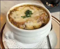  ?? Arkansas Democrat-Gazette/ERIC E. HARRISON ?? The onion soup gratinee comes in a cup or a bowl, both with flanking lion’s heads, at Atlas Bar.