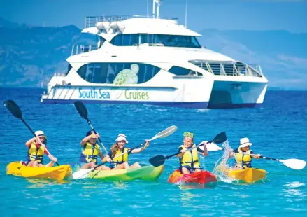  ??  ?? Visitors kayaking alongside one of South Sea Cruises vessels .