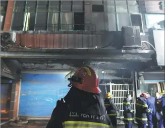  ?? ZHOU MI / XINHUA ?? Firefighte­rs work on Wednesday at the scene of a blaze, which killed 39 people, in Xinyu, Jiangxi province.