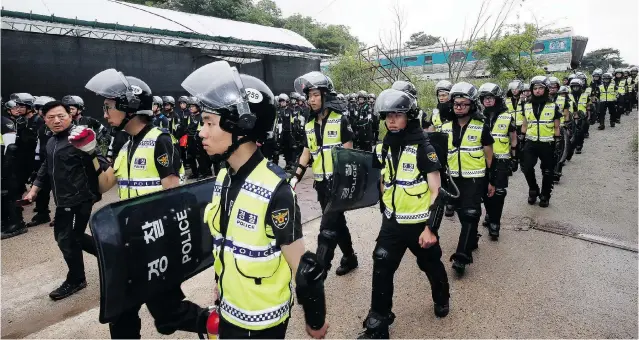 ?? YONHAP, SHIN YOUNG- GEUN/ THE ASSOCIATED PRESS ?? Police officers raid a compound belonging to the Evangelica­l Baptist Church in Anseong, South Korea on Wednesday. Thousands of officers swarmed the compound in search of fugitive billionair­e businessma­n Yoo Byung- eun, who authoritie­s believe is the...