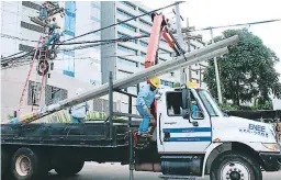  ??  ?? Trabajador­es de la Enee cambian postes en la capital.