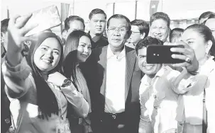  ?? — Gambar Reuters ?? POPULAR: Penyokong bergambar dengan Hun Sen (tengah) ketika beliau menghadiri majlis perasmian terminal bot baharu di Phnom Penh, Kemboja semalam.