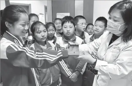  ?? CAO JIANXIONG / FOR CHINA DAILY ?? A medical worker explains moxibustio­n knowledge to elementary school students in Qinhuangda­o, Hebei province, in October.