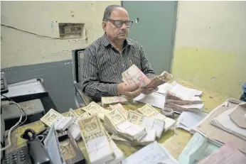  ??  ?? CASHING IN: An Indian Railways staff counts currency notes of 500 and 1,000 rupees from the sale of railway tickets, one of the few places still accepting the high denominati­on notes, in Allahabad.