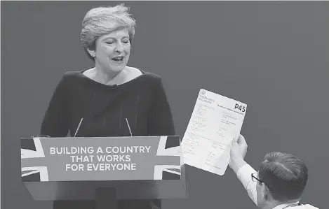  ?? PAUL ELLIS / AGENCE FRANCE-PRESSE / GETTY IMAGES ?? Protester/comedian Simon Brodkin gives a mock dismissal form to British Prime Minister Theresa May in Manchester on Wednesday.