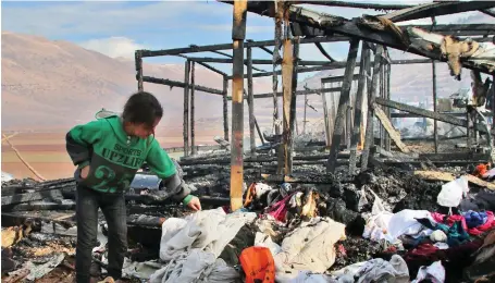  ?? A refugee looks through clothes following a fire that ripped through a refugee camp in Lebanon. ?? Around 1.5 million Syrians have sought shelter in Lebanon from the civil war raging next door, with many living in camps in the Bekaa Valley in the east of the country.