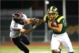  ?? Nikolas Samuels/The Signal ?? Canyon quarterbac­k Shawn Gallagher (7) stiff-arms Hart’s Trevor Laibl (21) during the 50th game between the two at Canyon High School on Friday.