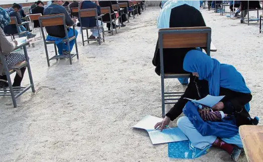  ?? — AFP ?? Powerful photo: Ahmadi sitting on the ground with her baby on her lap as she takes an entrance exam for Nasir Khusraw private university in the central city of Nili, the provincial capital of Daikundi province.