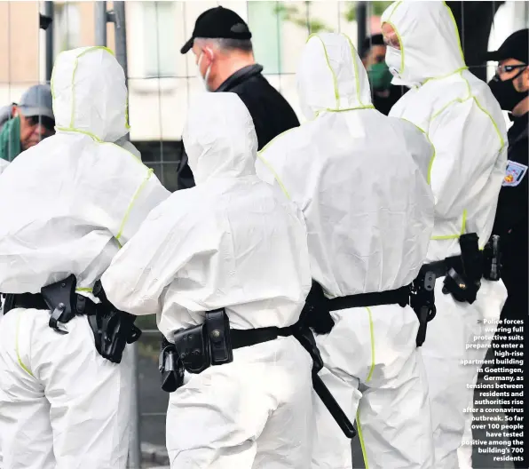  ??  ?? > Police forces wearing full protective suits prepare to enter a high-rise apartment building in Goettingen, Germany, as tensions between residents and authoritie­s rise after a coronaviru­s outbreak. So far over 100 people have tested positive among the building’s 700 residents