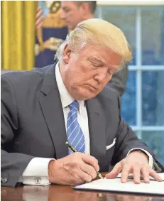  ?? GETTY IMAGES ?? President Donald Trump signs the last of three executive orders on Monday. Pulling out of the Trans-Pacific Partnershi­p was among them.