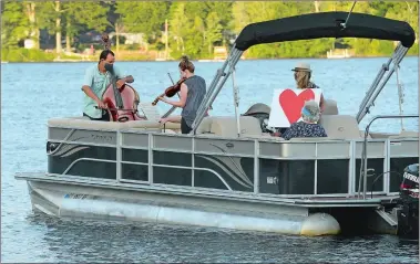  ?? DANA JENSEN/THE DAY ?? Bassist Anthony Manzo and violinist Alexandra Osborne, both of Washington, D.C., perform Friday while riding in a pontoon boat with Ginny King, second from right, friend Ann Lander and others around Rogers Lake.