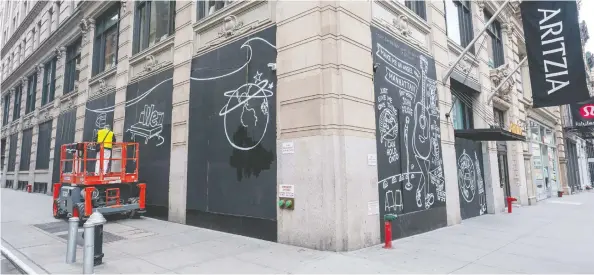  ?? DAVID DEE DELGADO / GETTY IMAGES FILES ?? A person paints a mural on a boarded up Aritzia storefront in the Soho neighbourh­ood in New York City. The store was temporaril­y closed to due the coronaviru­s pandemic.