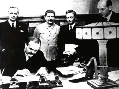  ?? (PHOTO12/UNIVERSAL IMAGES GROUP/GETTY IMAGES) ?? La signature du pacte à Moscou, par le ministre soviétique des Affaires étrangères, Viatchesla­v Molotov. Derrière lui, tout à gauche, son homologue allemand, Joachim von Ribbentrop, et Joseph Staline.