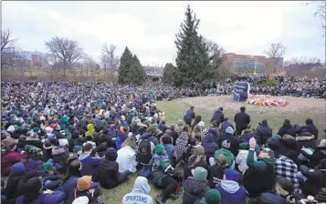  ?? PAUL SANCYA AP ?? Mourners sit at The Rock on the grounds of Michigan State University in East Lansing, Mich., on Wednesday, two days after a gunman killed students Alexandria Verner, Brian Fraser and Arielle Anderson.