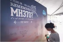  ?? VINCENT THIAN/ASSOCIATED PRESS ?? A girl writes a condolence message during the Day of Remembranc­e for the MH370 event in Kuala Lumpur, Malaysia, in March, marking the 4th anniversar­y of the jet’s disappeara­nce.