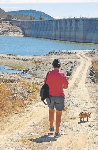  ?? J.M. BRAZO MENA ?? Un hombre y su perro pasean por el lecho del pantano de Aracena//