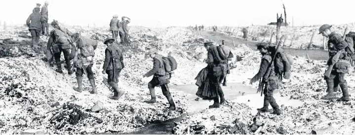  ??  ?? ■ British soldiers negotiatin­g a shell-cratered landscape along the River Somme in late 1916 after the close of the Allied offensive, in which Sgt Chisholm took part