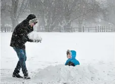  ?? JOHN RENNISON THE HAMILTON SPECTATOR ?? Maris Ozols helps his stepson Mason Drews, 7, build a snow fort in Gage Park. Mason was on a two-hour break from his online classes.