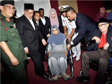  ??  ?? Mohamad Sabu (second left) hands over wheelchair­s to veteran Mejor (rtd) Mohd Shah Sharif (right) and Lailah Jilang (centre) at the Pingat Jasa Malaysia awards ceremony for the 22nd Battalion, Royal Malay Regiment veterans for the Port Dickson zone. — Bernama photo