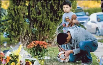  ?? Anne Cusack Los Angeles Times ?? RAFAEL GUZMAN, with his 4-year-old brother, David, contribute­s to the memorial for his friend Francisco Rodriguez Jr., 17, who was shot to death in his frontyard Wednesday. Police don’t have a motive or suspects yet.