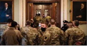  ?? (The New York Times/Erin Schaff) ?? Members of the Pennsylvan­ia National Guard look in on Senate proceeding­s Friday at the U.S. Capitol.