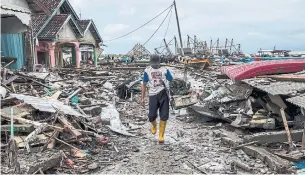  ?? KEMAL JUFRI THE NEW YORK TIMES ?? A man surveys the aftermath of the tsunami that hit Sumur, Indonesia. At least 429 people died and nearly 1,500 were injured by the powerful waves.