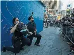  ??  ?? 在纽约时报广场，名警察在和平集会游行­现场单膝下跪，其中女警还比出爱心手­势。（法新社照片）