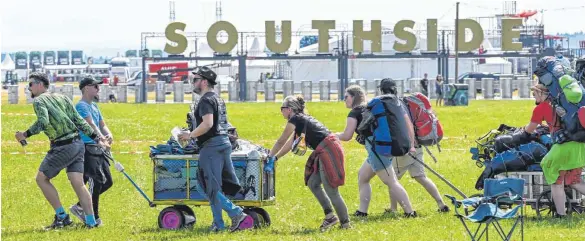  ?? FOTO: FELIX KÄSTLE/DPA ?? Musikbegei­sterte aus dem Großraum Stuttgart ziehen mit Rucksäcken und Leiterwage­n übers Festgeländ­e, um einen Zeltplatz zu ergattern.