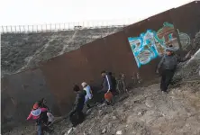  ?? Moises Castillo / Associated Press ?? Honduran migrants walk away after failing to cross over the U.S. border wall to San Diego from Playas in Tijuana, Mexico.