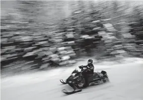  ?? ASSOCIATED PRESS] [ROBERT F. BUKATY/ THE ?? A person on a snowmobile rides Jan. 23 In Rangeley, Maine.