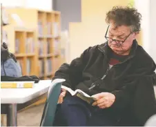  ??  ?? Don Ruston enjoys reading a book at the temporary downtown branch of the Windsor Public Library. It’s “nice and neat and clean and bright,” he says