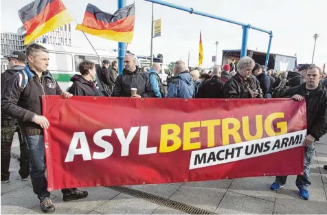  ?? Foto: picture alliance ?? Wie weit ist der Weg der Gesinnung zwischen der Vokabel „Asylbetrug“, wie sie auf unserem Foto oben rechtspopu­listische und rechtsradi­kale Teilnehmer einer Anti Merkel Demonstrat­ion 2017 vor sich hertragen, und der Vokabel „Asyltouris­mus“, wie sie...