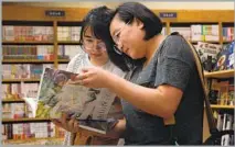  ??  ?? MICHELLE PHAM, left, and Vyvy Pham look at a Japanese art book at Kinokuniya Los Angeles, which also has novelty items.