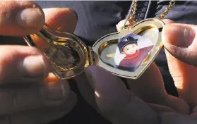  ?? Lea Suzuki / The Chronicle ?? Jeannie Atienza holds a locket with a photograph of her son Laudemer Arboleda. “I just can’t accept that he’s gone,” Atienza said, kneeling in the grass by her son’s grave last year in Hayward.