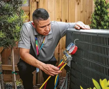  ?? Reliant Energy ?? Reliant Home Services technician Argelio Garcia checks an outdoor condensing unit at a customer’s home.